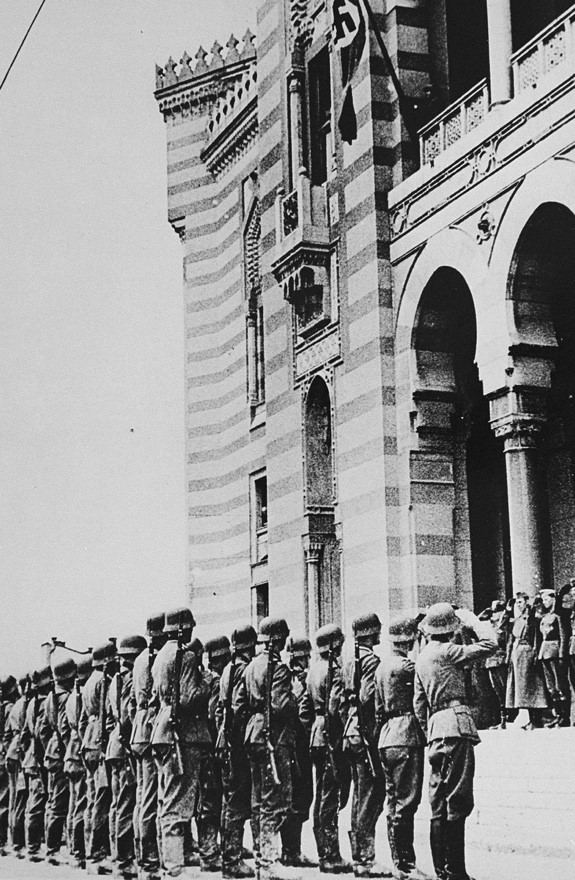 German troops salute during a flag raising ceremony on the balcony of Sarajevo city hall